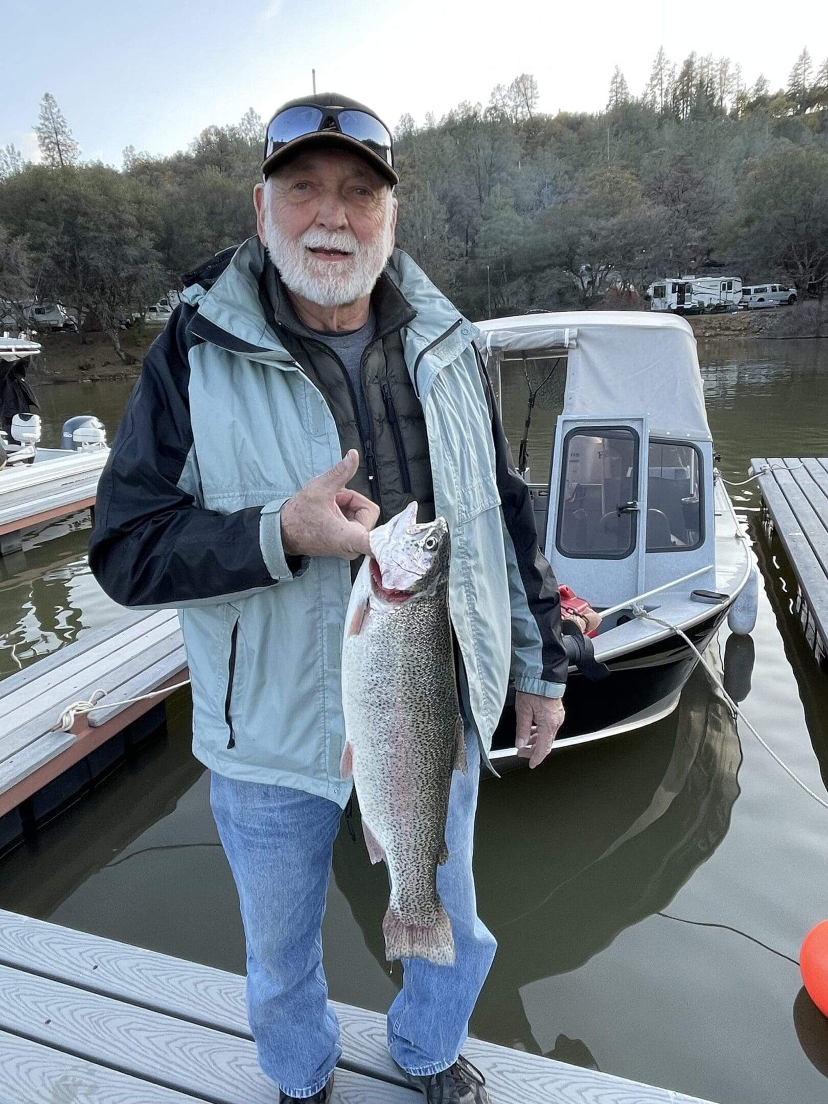 Man proudly holding a large fish by the water.