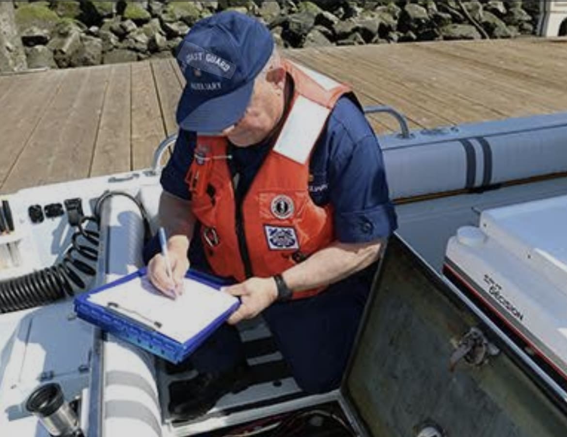 A man in uniform writing on a clipboard on a boat.