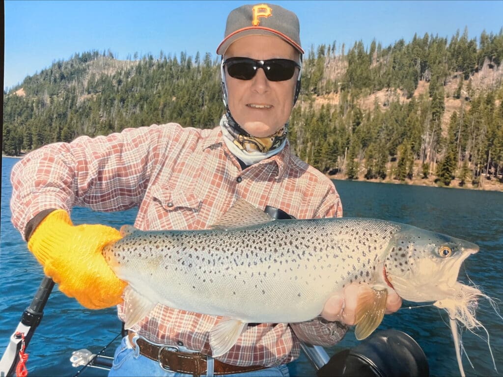 Man proudly holding a large fish he caught outdoors.