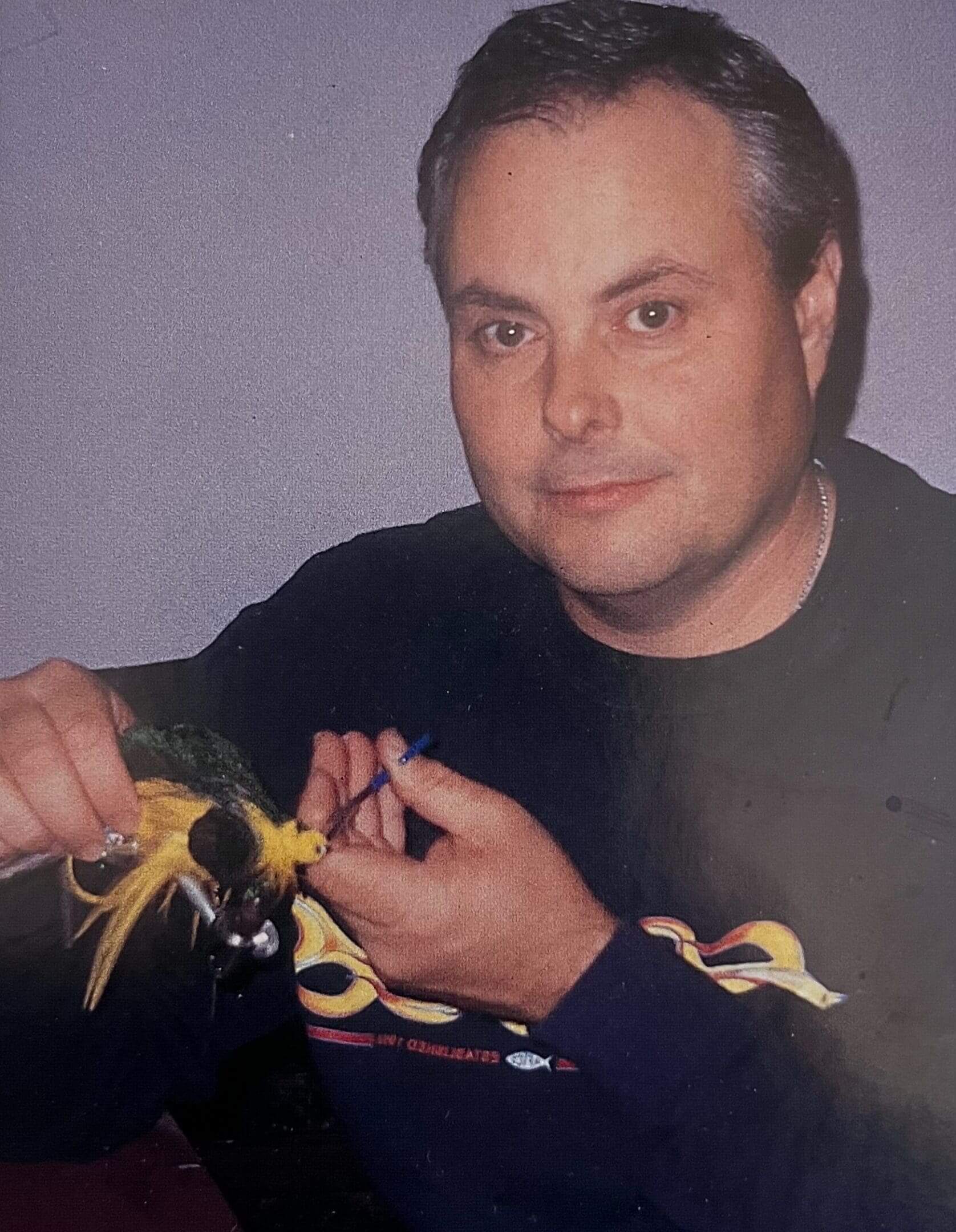 Man holding a large insect, looking at the camera.