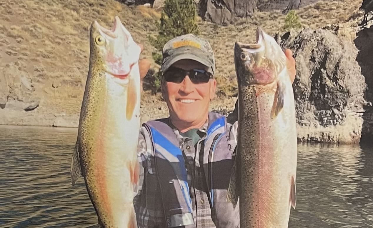 Man proudly holding two large fish caught while fishing.