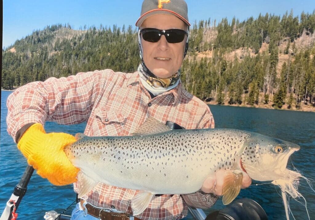 Man proudly holding a large fish he caught outdoors.